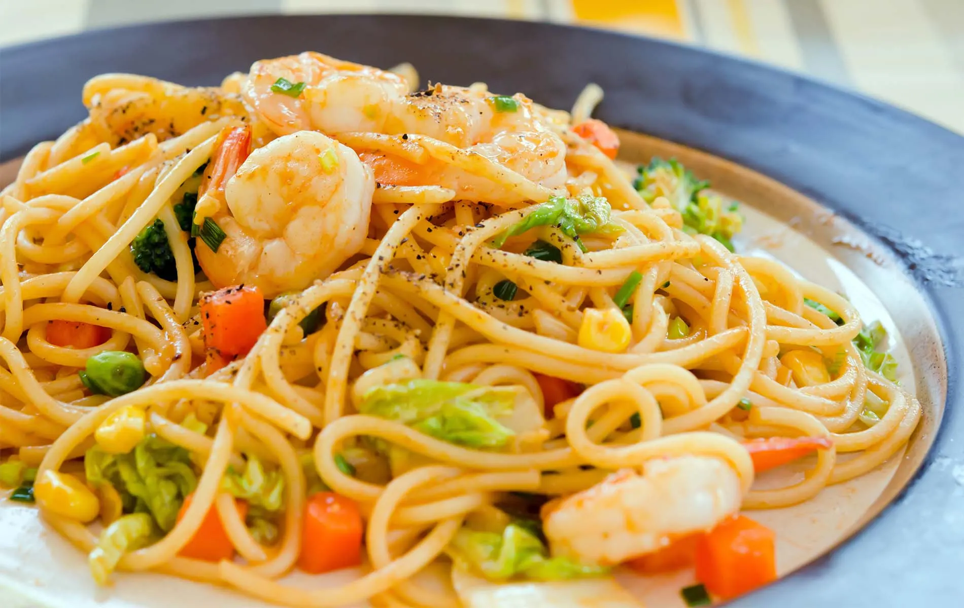 Spaghetti with shrimp, broccoli and carrots on a plate