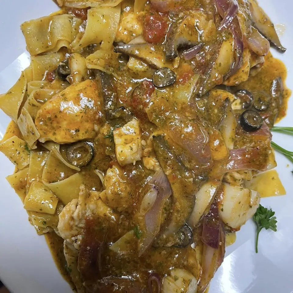 A plate of pasta with chicken, mushrooms and red onion in a light sauce