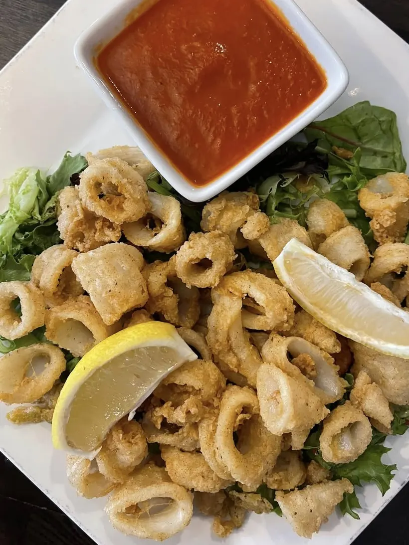 Fried calamari with marinara sauce and a lemon wedge