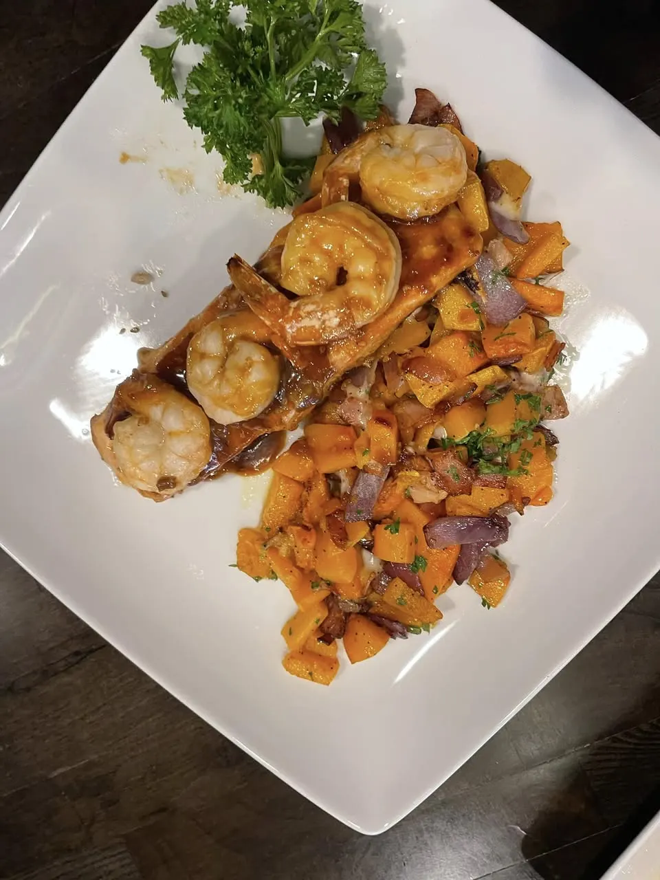 Shrimp over roasted sweet potatoes on a square plate