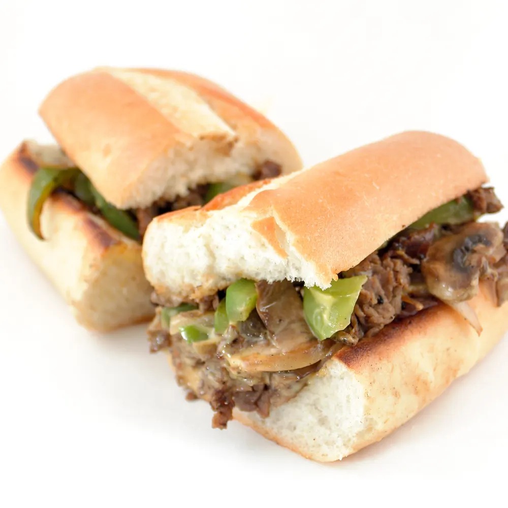 A cheesesteak with green peppers and mushrooms on a toasted roll